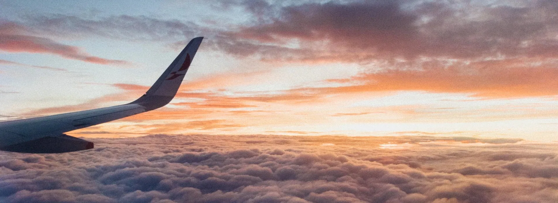 Aircraft wing above the clouds at sunset