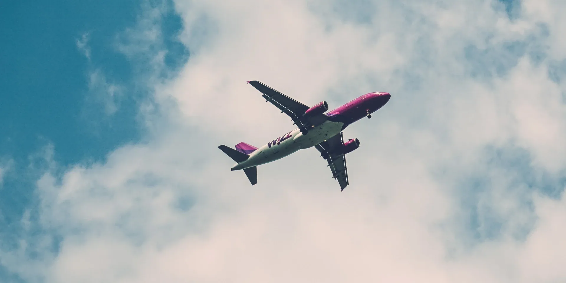 Passenger jet flying overhead against a blue sky with clouds